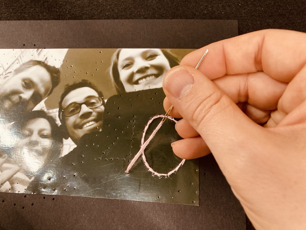 Auf ein Foto wird mit rosa Faden eine Zahl gestickt