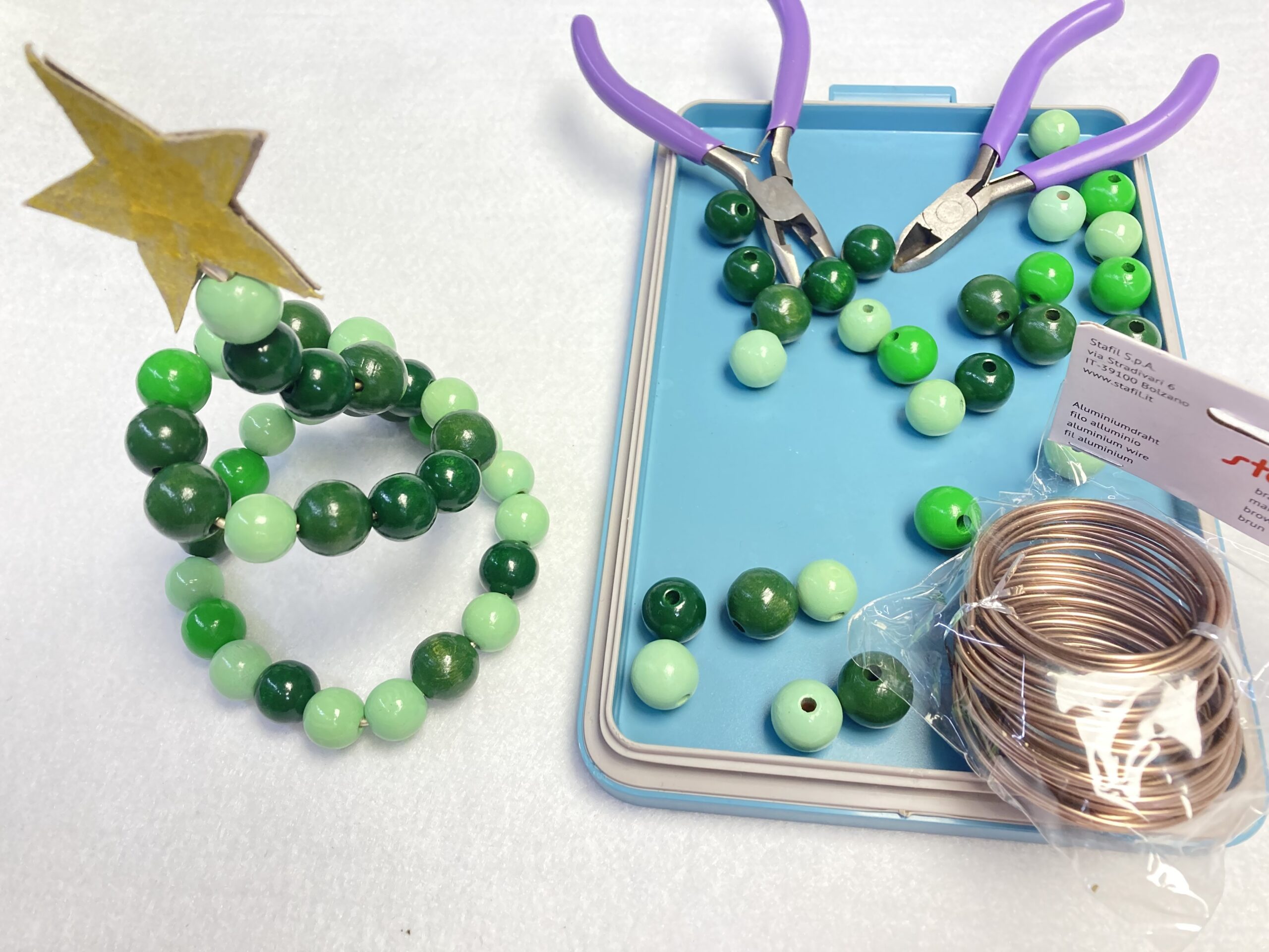 Holzperlenbäumchen mit Holzperlen, Draht, Zangen auf einem Tisch