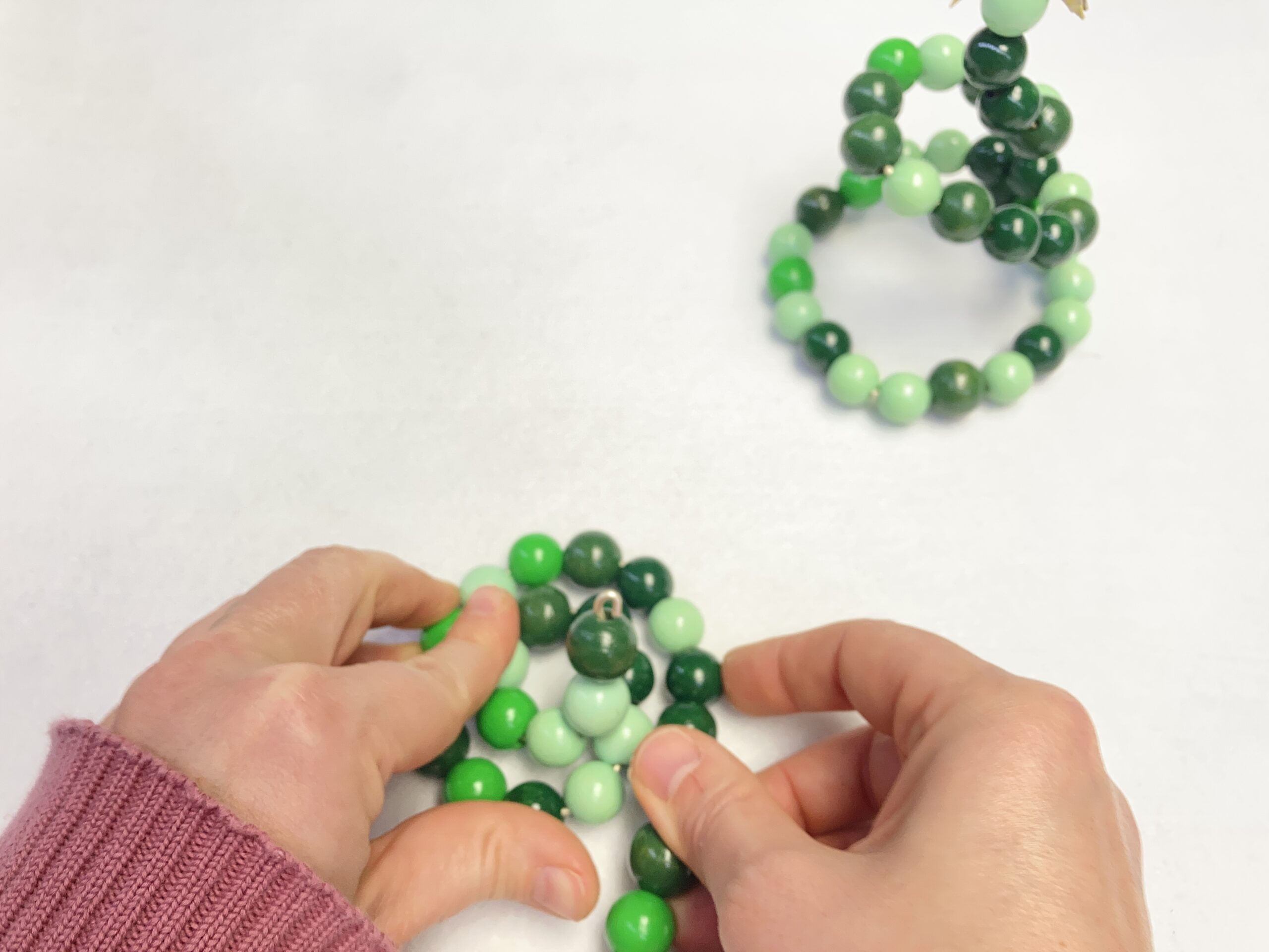 Draht mit aufgefädelten Holzperlen wird zu einer Spirale gebogen