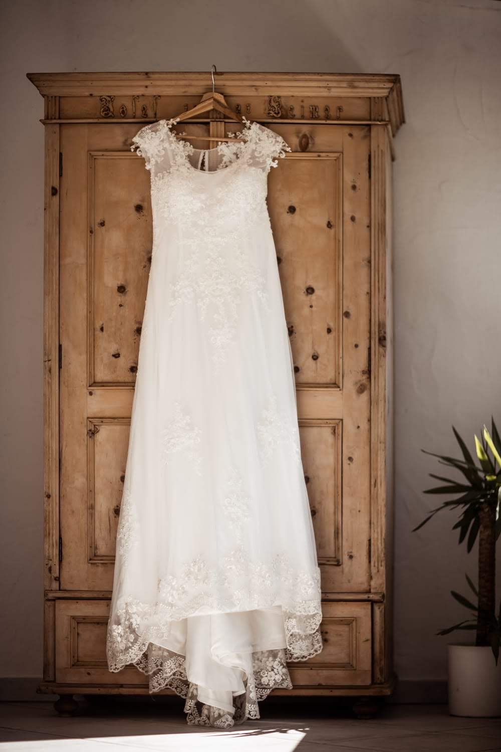 Brautkleid hängt am Bügel auf einem Schrank